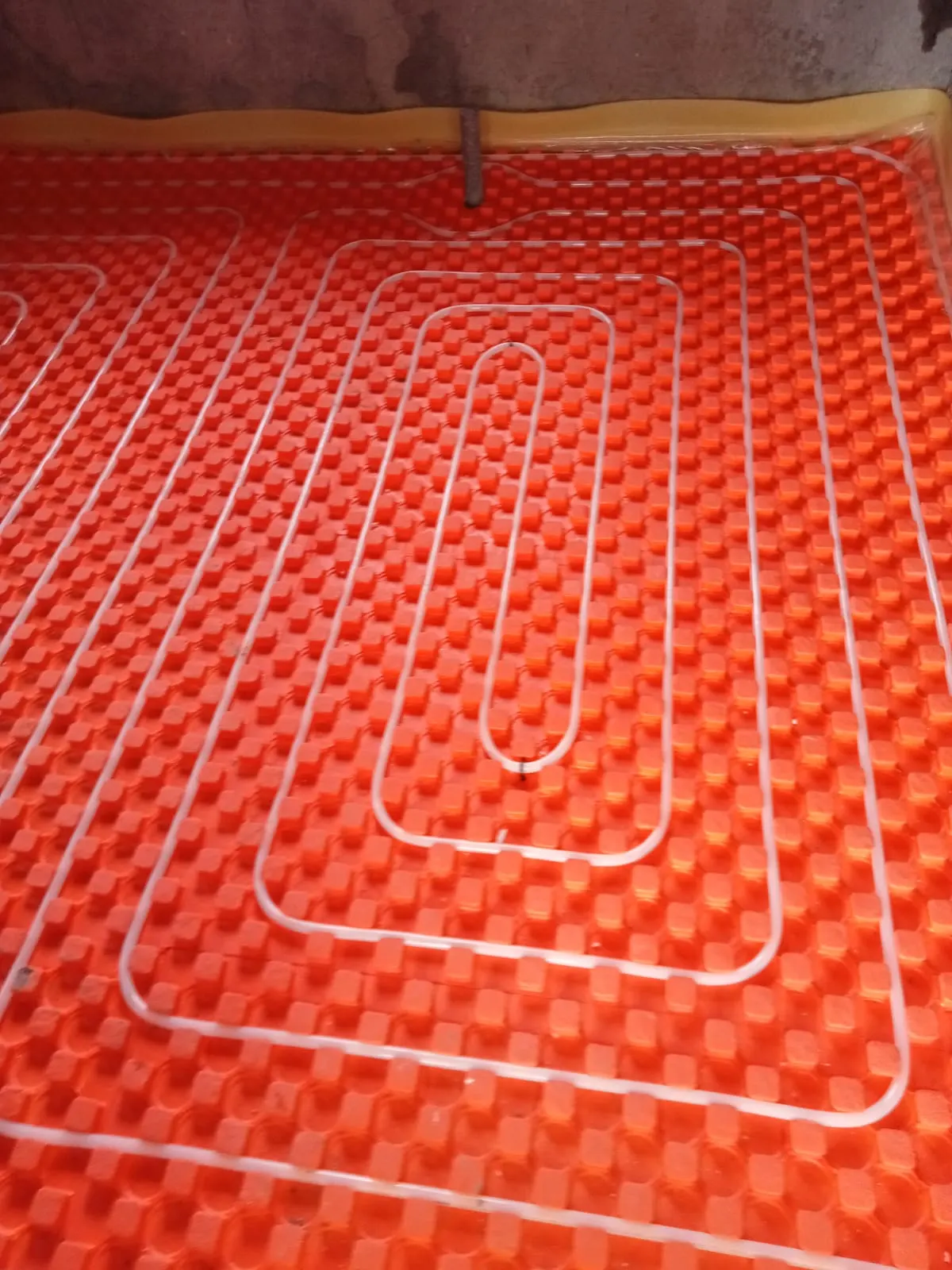 Plancher chauffant : tube serpentin posé sur panneau isolant