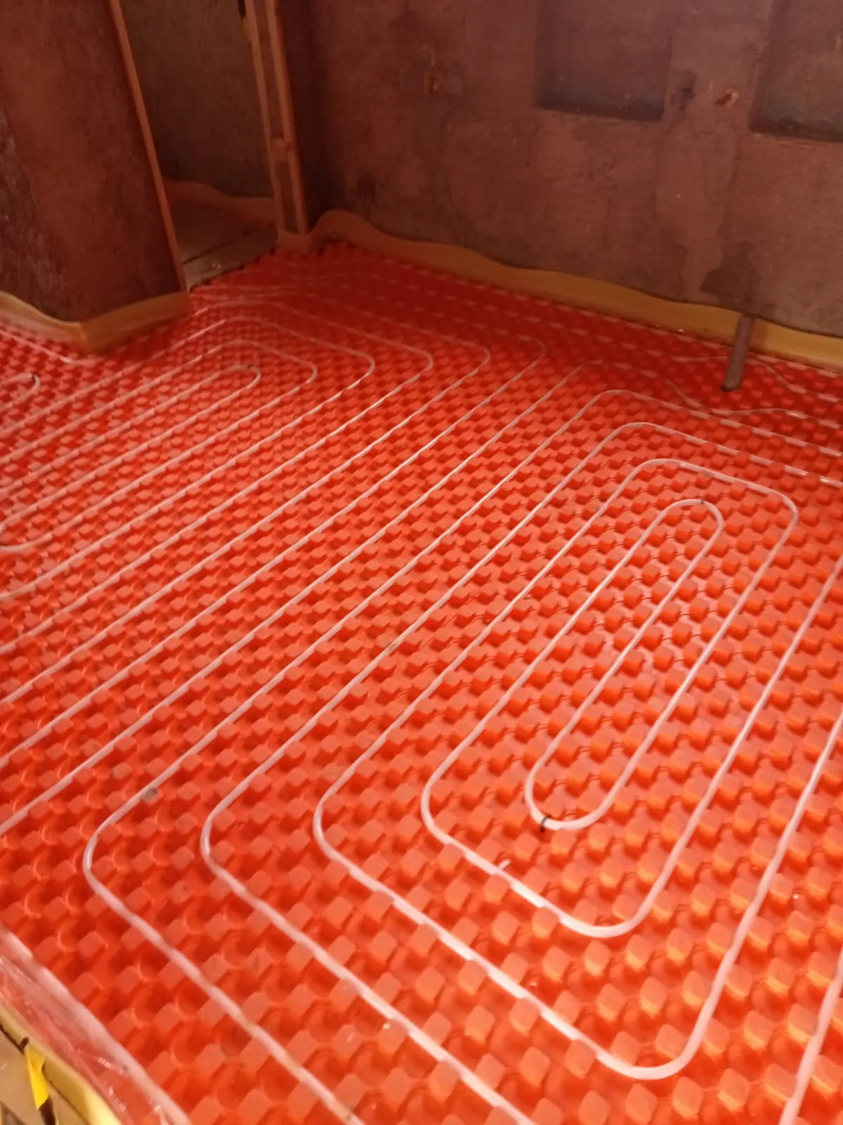 Pose du réseau de plancher chauffant dans une pièce en cours de finition